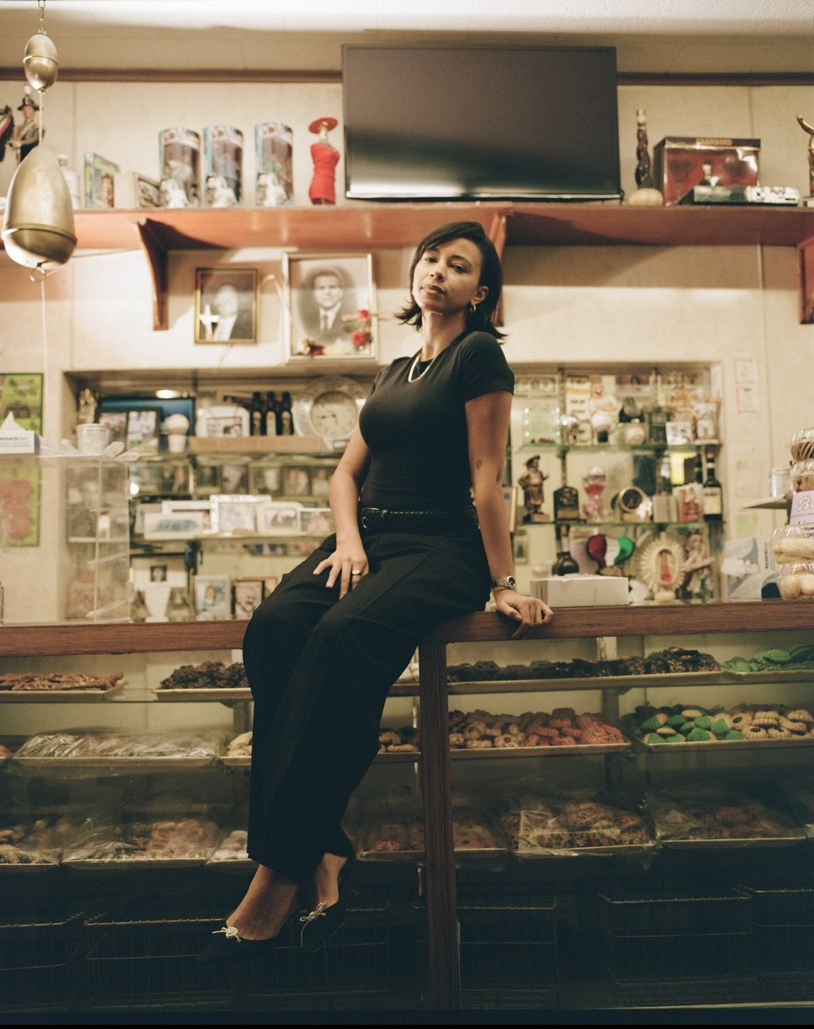 Sitting on a bakery counter in Black trousers