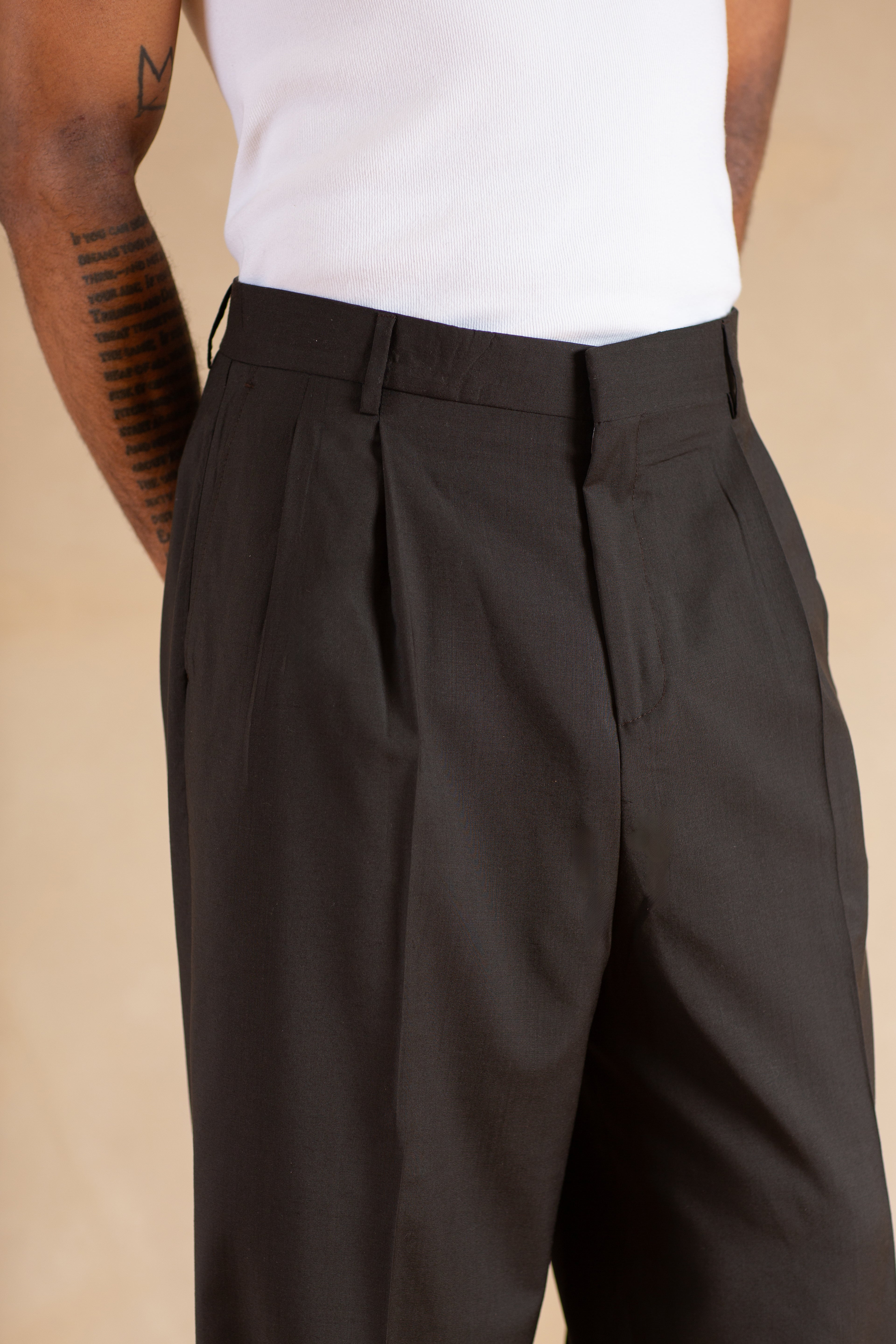Person wearing Stone pleated pants on a beige background