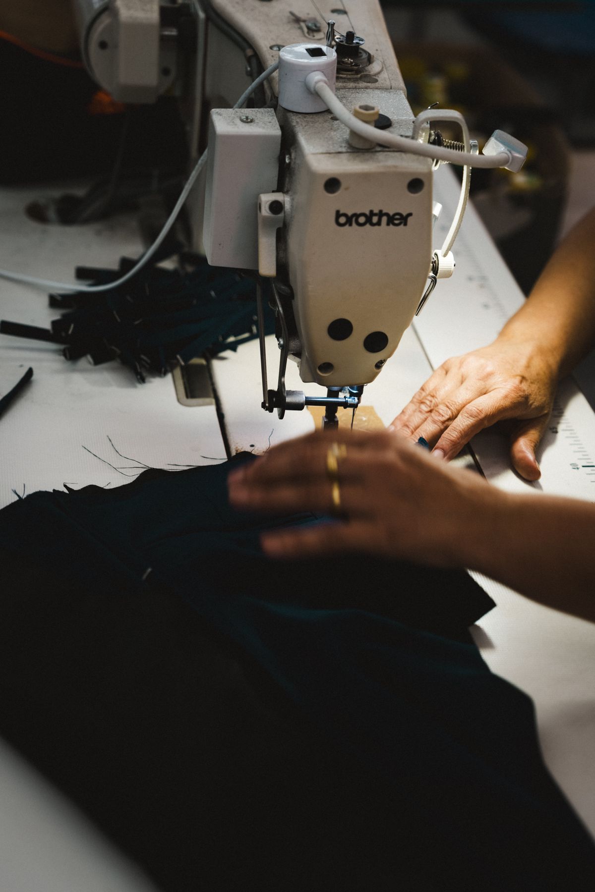Hands guiding Italian wool through a sewing machine