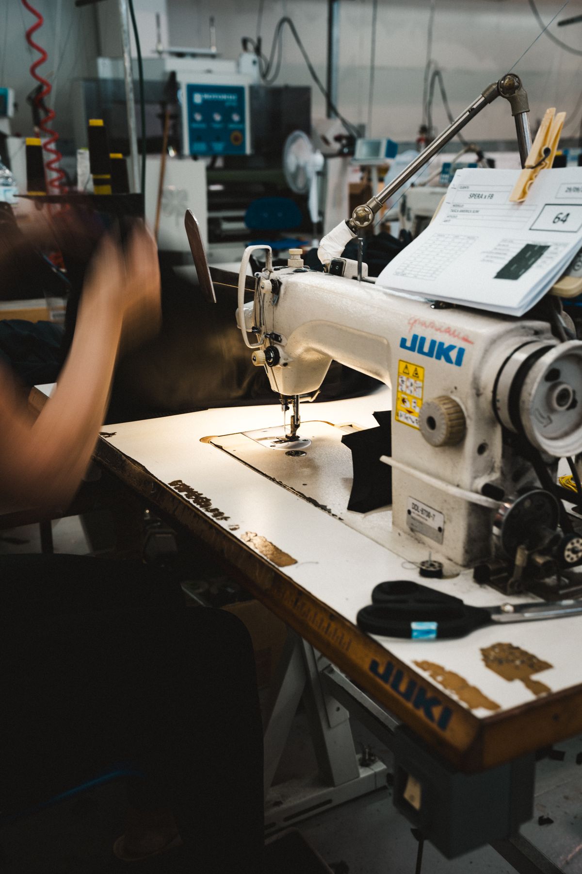 A seamstress at her sewing machine on the factory floor
